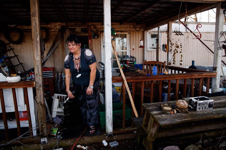 Melissa Keller pets her dog, shadow, as she looks around her destroyed property following a tornado in Hohenwald, Tenn. on Mar. 31, 2023.