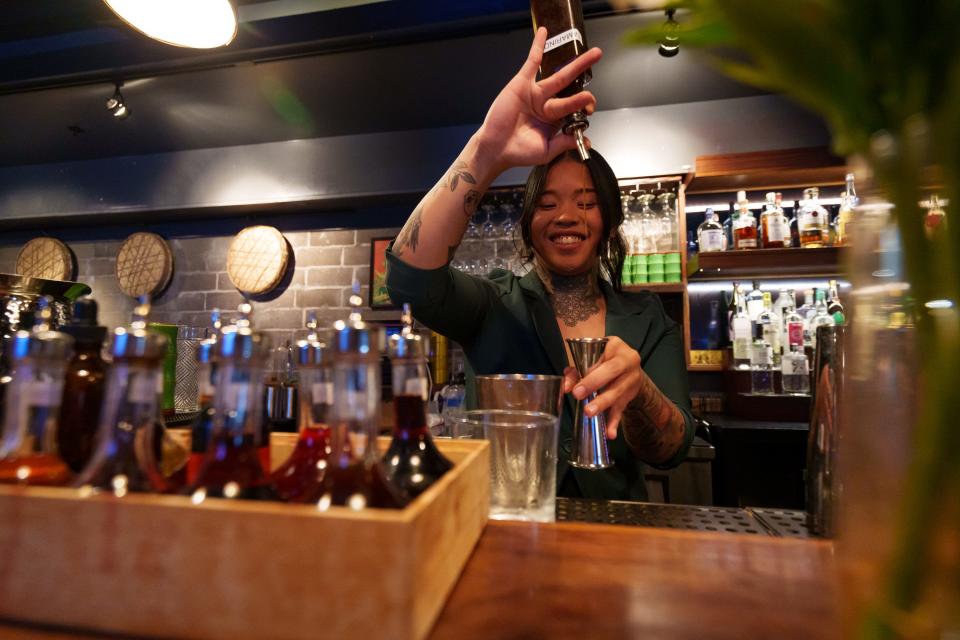 Alyssah Padua makes a cocktail behind the bar at Mr. Baan's Bar and Mookata in Phoenix.