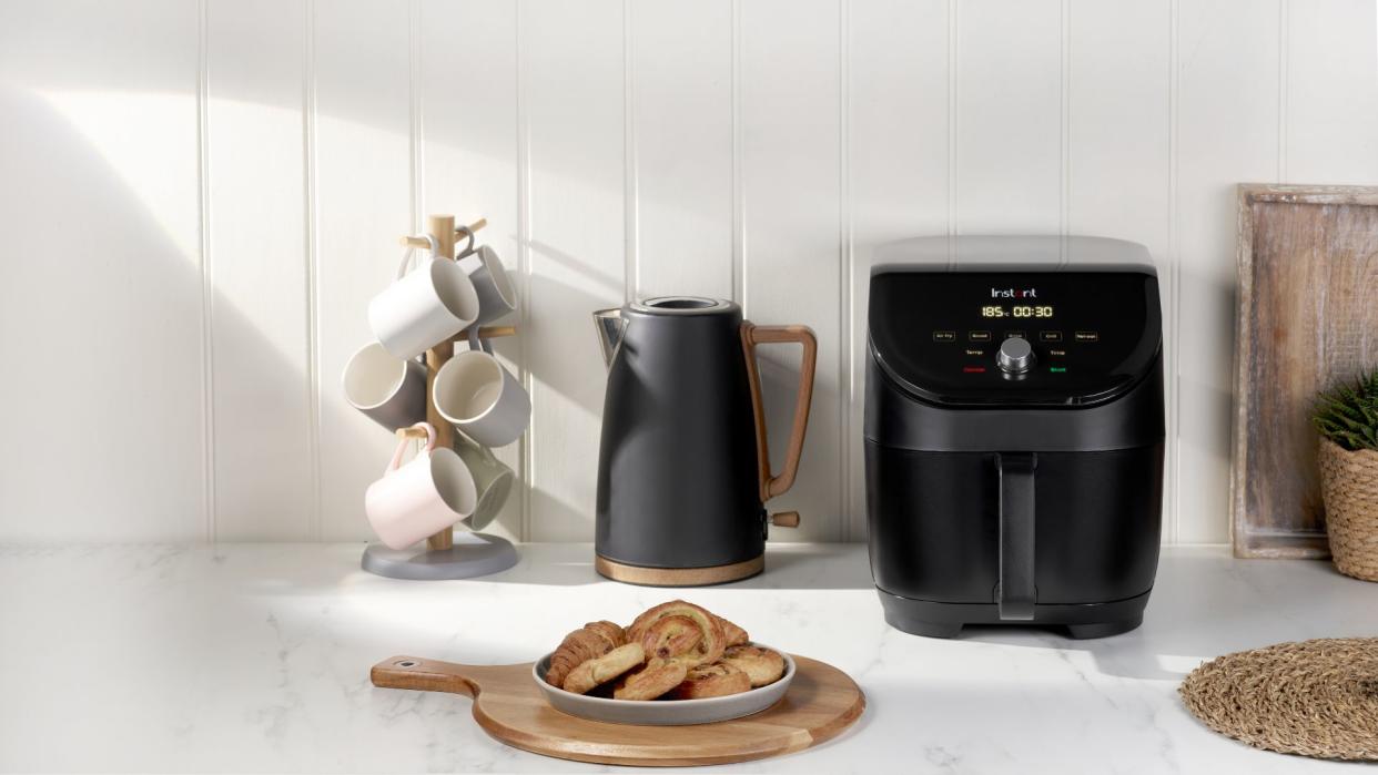  An Instant Vortex Slim air fryer on a countertop next to an electric kettle and a plate of cinnamon rolls 