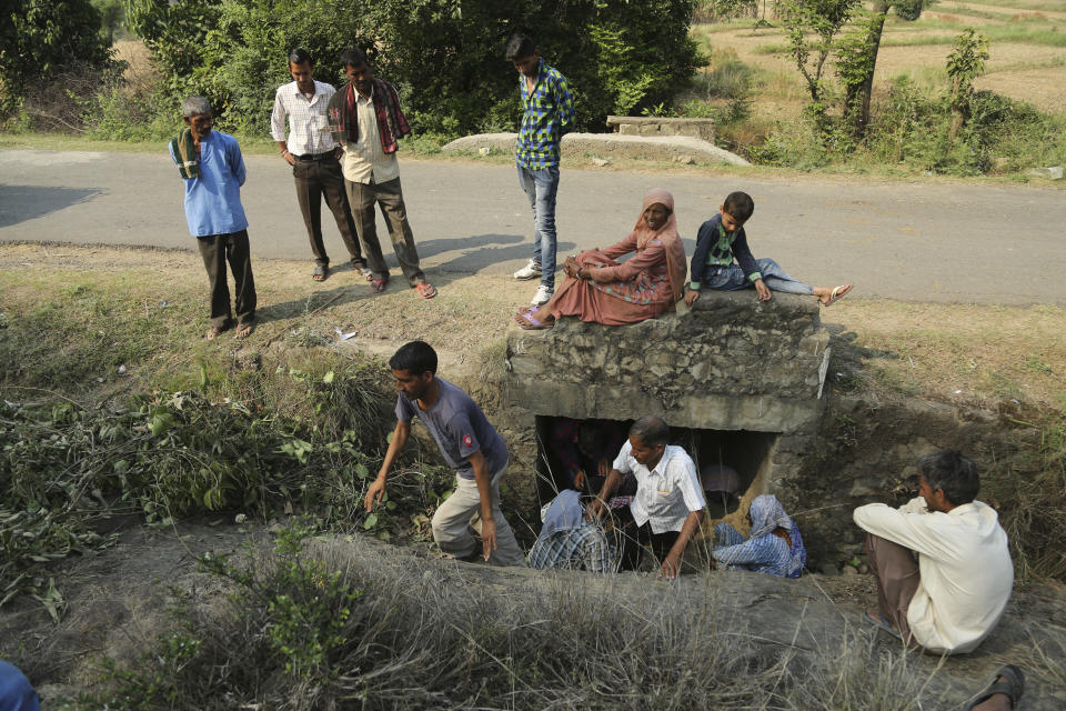 FILE - In this May 14,2017, file photo, Indian civilians take temporary shelter beneath a culvert as they wait for transport to move to safer places after mortar shells were fired allegedly from the Pakistan side of the border, at a residential area near Line of Control on the India Pakistan border at Jhanghar village, in Nowshera, India. The Line of Control, a highly militarized de facto border that divides the disputed region between the two nuclear-armed rivals India and Pakistan, and a site of hundreds of deaths, is unusually quiet after the two South Asian neighbors agreed in February, 2021, to reaffirm their 2003 cease-fire accord. (AP Photo/Channi Anand, File)