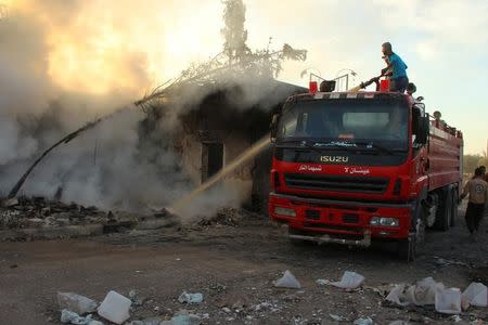 A Civil Defence member and a man put out a fire after an airstrike on the rebel held Urm al-Kubra town, western Aleppo city, Syria September 20, 2016. REUTERS/Ammar Abdullah