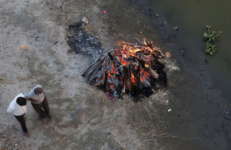 People watch as a pyre burns on the banks of river Ganges in Kanpur, India, April 3, 2017. REUTERS/Danish Siddiqui