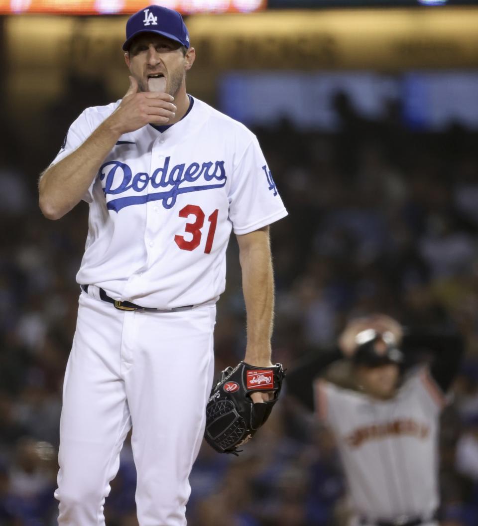 Los Angeles Dodgers starting pitcher Max Scherzer licks his fingers while preparing to pitch