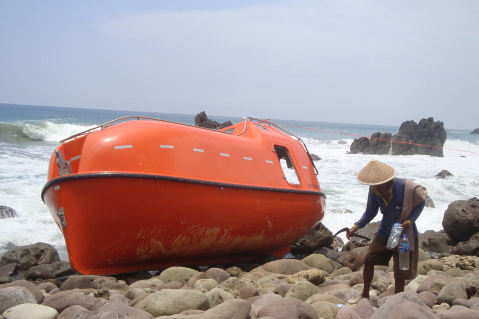 A man walks near a lifeboat which is stranded on Karangjambe beach in Kebumen, Central Java Indonesia, Tuesday, Feb 25, 2014. Asylum seekers in the lifeboat who were stranded on Indonesia's Java island said that Australian authorities turned them away and exploded the boat that carried them to Christmas Island. The asylum seekers are now at an immigration centre in Kebumen, (AP Photo)
