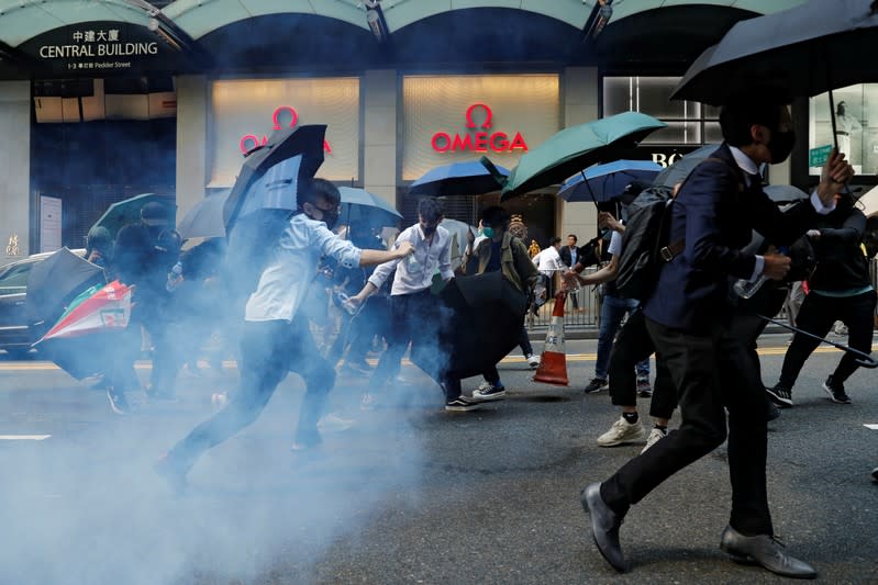 Office workers run away from tear gas as they attend a flash mob anti-government protest at the financial Central district in Hong Kong