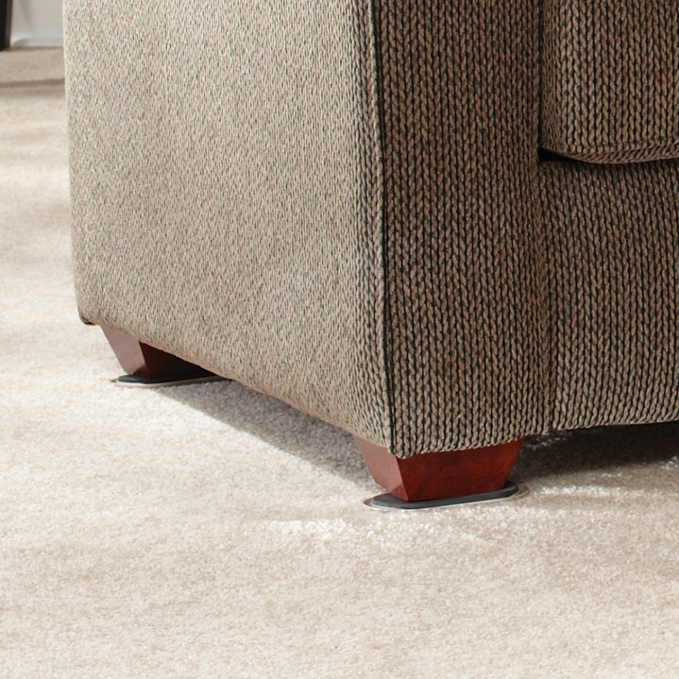 Close-up of a couch's foot showing a furniture coaster below it, used to protect floor surfaces