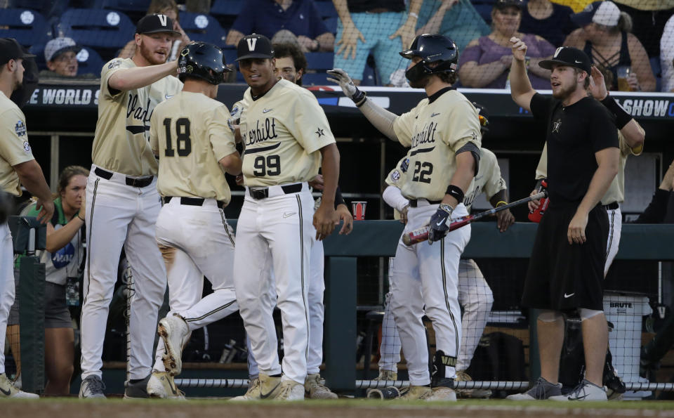 Vanderbilt's Pat DeMarco (18) is congratulated by teammates after scoring a run against Michigan during the seventh inning of Game 3 of the NCAA College World Series baseball finals in Omaha, Neb., Wednesday, June 26, 2019. (AP Photo/Nati Harnik)
