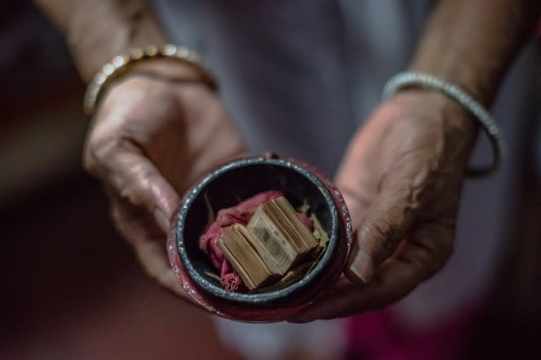 Shah Jahan Begum, 65, the wife of Indian Partition survivor Saleem Hasan Siddiqui, poses for a photograph with a miniature Koran his family saved during Partition at the home where he has lived since Partition in New Delhi