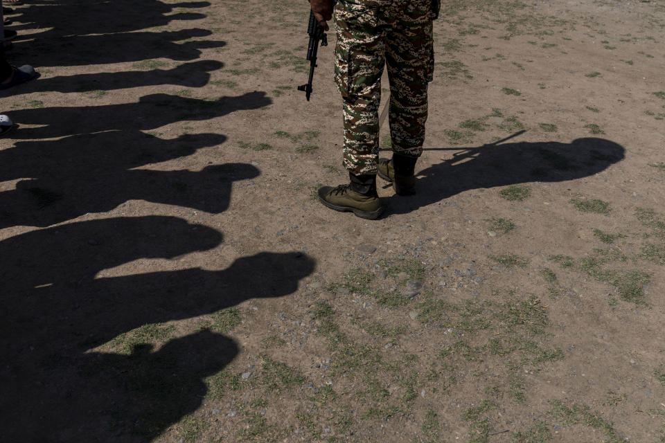 A paramilitary soldier stands guard near Kashmiri villagers standing in a queue to vote outside a polling booth, during the fifth round of multi-phase national election in Rathson village, west of Srinagar, Indian controlled Kashmir, Monday, May 20, 2024. (AP Photo/Dar Yasin)