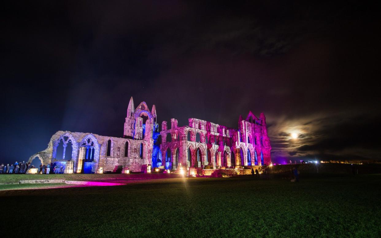 Whitby Abbey's exterior bathed in colourful lights.