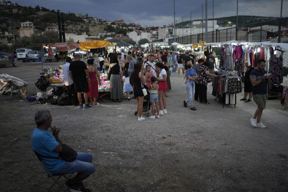 People visit a flea market for shopping during a festivity, known as Panigiri, in Hasia, northwestern Athens, Greece, Sunday, Aug. 14, 2022. The Dormition of the Virgin Mary (or Mother of God as the Greeks usually refer to her) is celebrated on Aug. 15. The religious event is coupled with midsummer festivities, known as Panigiria, that often last more than a day with music, culinary feasts and, in many cases, flea markets. (AP Photo/Thanassis Stavrakis)