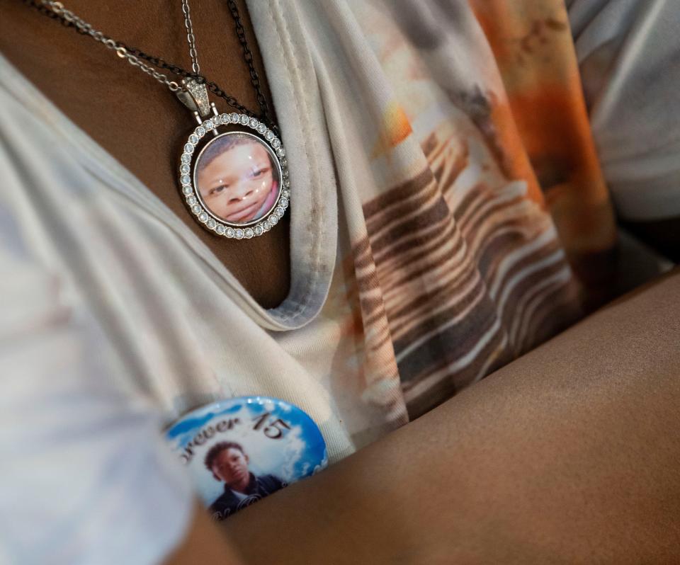 Chrystyna McGibboney wears a button and pendant bearing photos of her son, Devin Gilbert III, Wednesday, Dec. 13, 2023, at the Bishop Law Firm in Indianapolis. Since the 15-year-old was shot after leaving school on Nov. 3, 2023, his mother keeps his photos close. “He was my son and he was my sunshine,” she said.