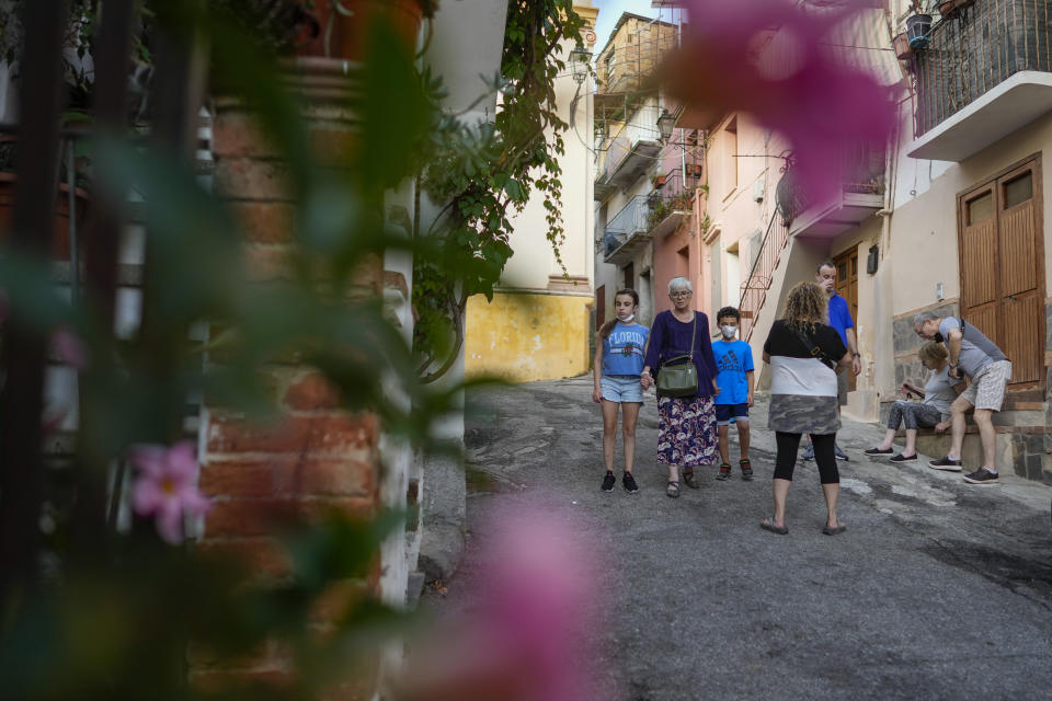 Rabbi Barbara Aiello holds hand with Mia Blum, 12, left, and her brother Noah Blum, 10, as she guides them with their family for a tour of the Jewish quarter of Lamezia Terme, southern Italy, Thursday, July 7, 2022. From a rustic, tiny synagogue she fashioned from her family's ancestral home in this mountain village, American rabbi Aiello is keeping a promise made to her Italian-born father: to reconnect people in this southern region of Calabria to their Jewish roots, links nearly severed five centuries ago when the Inquisition forced Jews to convert to Christianity. (AP Photo/Andrew Medichini)