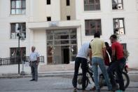 People stand in front of an apartment building which was damaged by a rocket fired from Syria, in Nusaybin