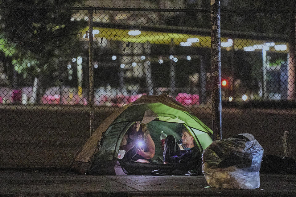 People sit inside a tent set on a sidewalk near City Hall downtown Los Angeles early morning Wednesday, June 26, 2024. The number of homeless residents counted in Los Angeles County has dipped slightly, decreasing by about 0.3% since last year as California continues to struggle with the long-running crisis of tens of thousands of people sleeping in cars and encampments. (AP Photo/Damian Dovarganes)