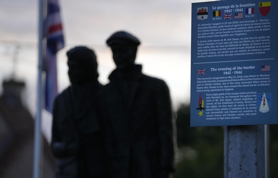 An information board and a statue depicting Henriette Hanotte helping American pilot Charles Carlson stands in the center of the town of Bachy, France, Friday, Sept. 16, 2022. Hanotte was a Belgian resistance member during World War II and from the age of nineteen aided the escape of nearly 140 airmen from occupied Belgium into France as part of the Comet Line. (AP Photo/Virginia Mayo)