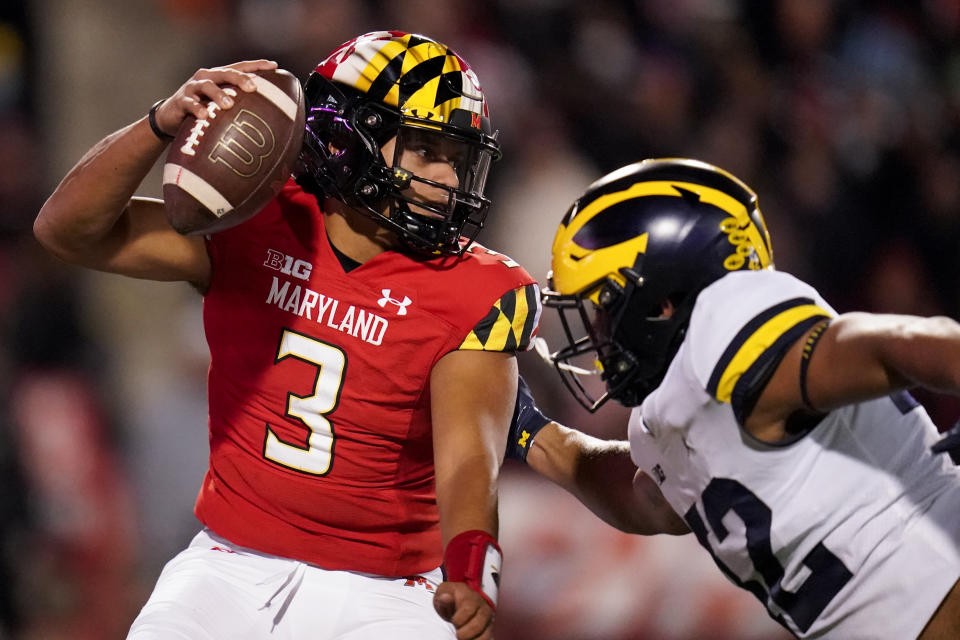 Maryland quarterback Taulia Tagovailoa, left, tries to avoid a sack by Michigan defensive end TJ Guy during the first half of an NCAA college football game, Saturday, Nov. 20, 2021, in College Park, Md. Michigan won 59-18. (AP Photo/Julio Cortez)