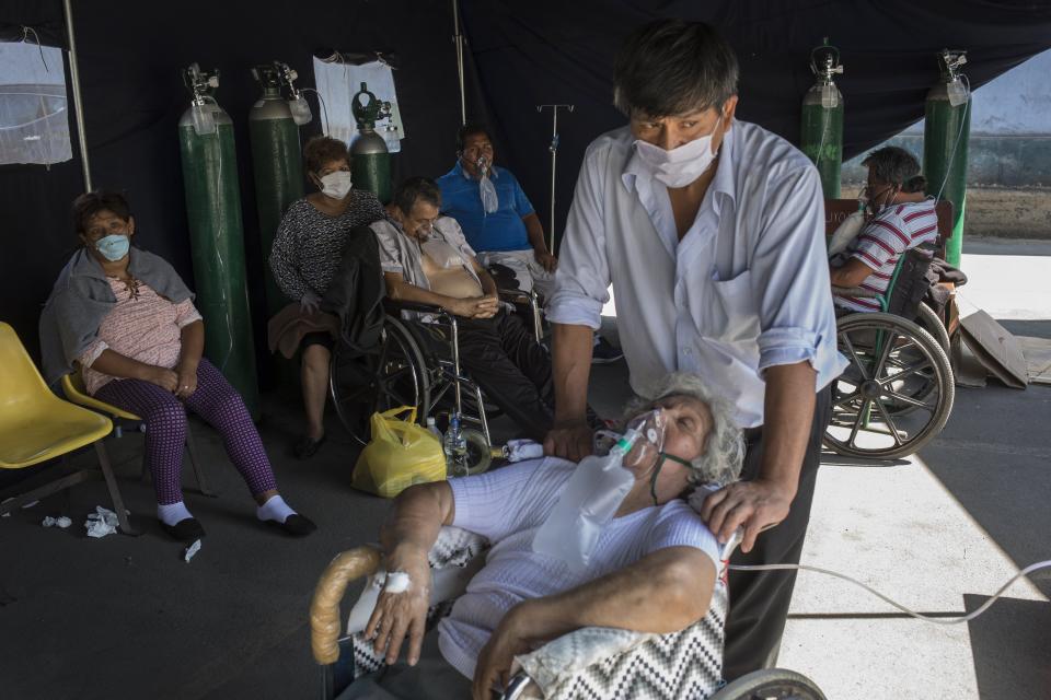 Emma Salvador, 84, supplements her oxygen as her son Jose Gonzalez watches over her in a makeshift tent set up at the 2 de Mayo Hospital to treat people who are infected with the new coronavirus, in Lima, Peru, Friday, April 17, 2020. (AP Photo/Rodrigo Abd)