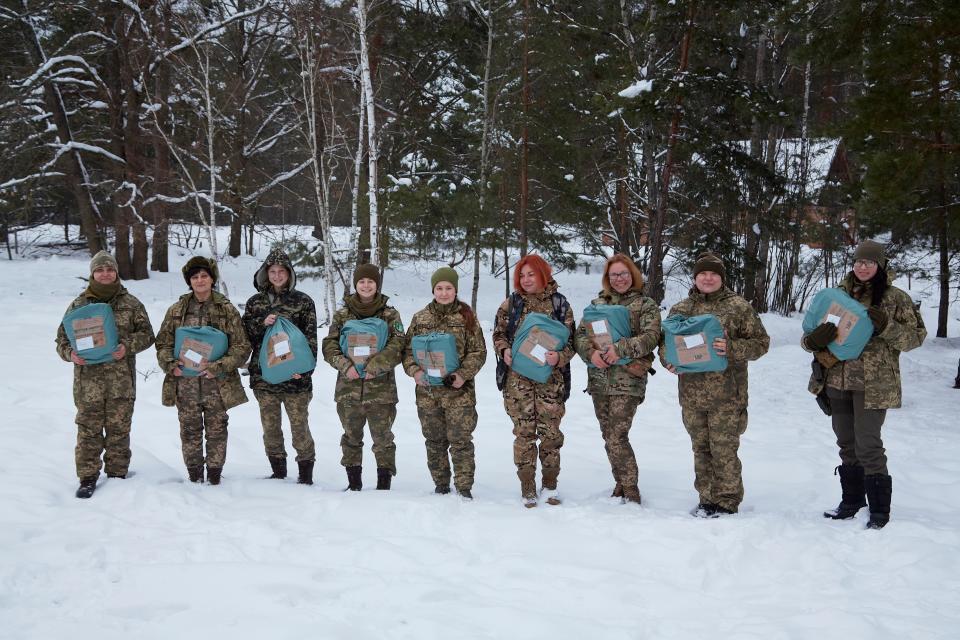 Several female Ukrainian soldiers pose for a photo while holding their Zemliachky humanitarian boxes.