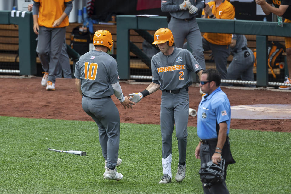 Tennessee Pete Derkay, left, celebrates with Max Ferguson, right, after scoring against Texas in the fourth inning of an NCAA college baseball game in the College World Series Tuesday, June 22, 2021, at TD Ameritrade Park in Omaha, Neb. (AP Photo/John Peterson)