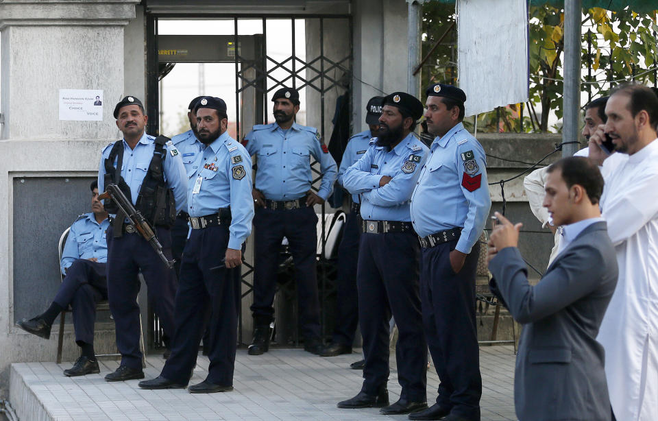 Pakistani police officers stand guard while supporters of Pakistan's ailing former Prime Minister Nawaz Sharif gather at an entrance of Islamabad High Court, in Islamabad, Pakistan, Saturday, Oct. 26, 2019. An Islamabad court is holding an emergency hearing to decide whether to free Sharif, convicted on money-laundering and corruption at charges. (AP Photo/Anjum Naveed)