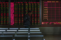 An investor walks by an electronic screen displaying stock prices at a brokerage house in Beijing, Wednesday, Oct. 23, 2019. Asian stock markets followed Wall Street lower Wednesday after major companies reported mixed earnings and an EU leader said he would recommend the trade bloc allow Britain to delay its departure. (AP Photo/Andy Wong)