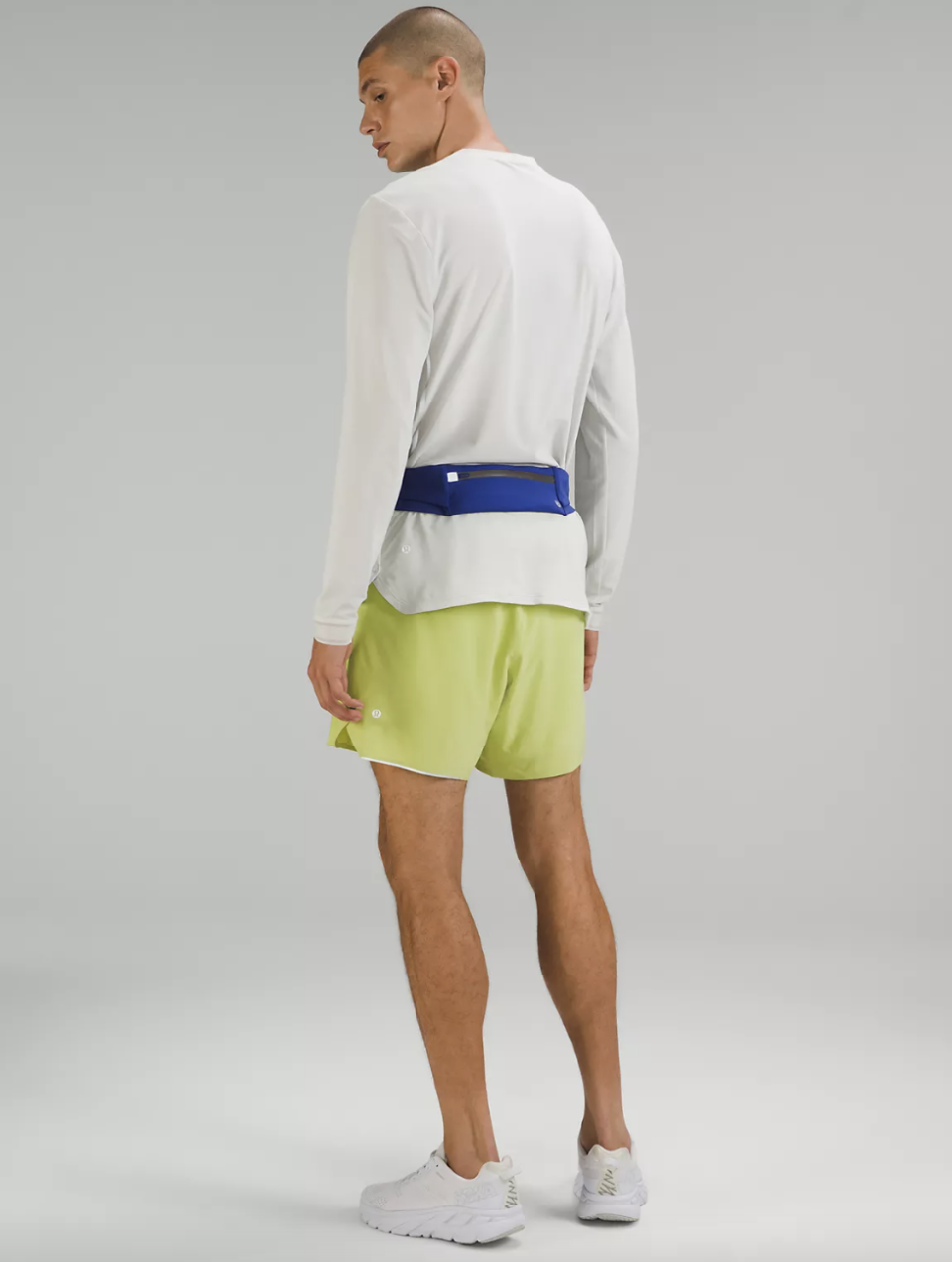 man wearing white shirt, green shorts and blue Fast and Free Running Belt in psychic (photo via Lululemon)