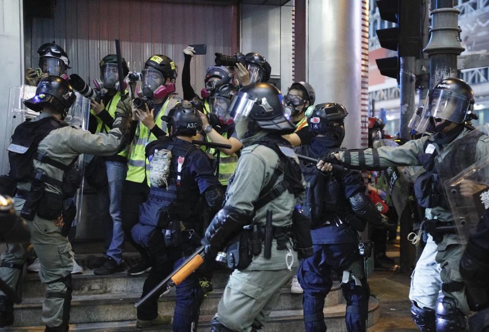 Hong Kong police officers push back journalists during a rally in Hong Kong on Sunday, Oct. 27, 2019. Hong Kong police fired tear gas Sunday to disperse a rally called over concerns about police conduct in monthslong pro-democracy demonstrations, with protesters cursing the officers and calling them "gangster cops." (AP Photo/Kin Cheung)