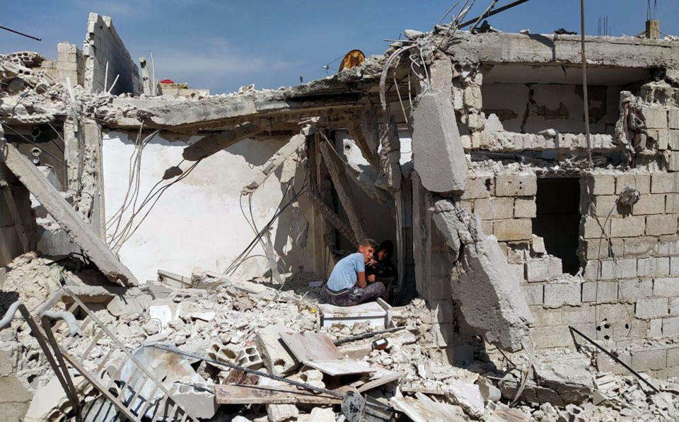 In this photo released by the Syrian official news agency SANA, boys sit amid the rubble of a house that according to the Syrian authorities was attacked by an Israeli airstrike, in the Damascus suburbs of Hajira, Syria, Monday, April 27, 2020. The Syrian military and state media said Monday that Israeli warplanes flying over Lebanon fired missiles toward areas near the Syrian capital of Damascus, killing three civilians. An opposition war monitor says four Iran-backed fighters were also killed. The military says Syrian air defenses shot some of the missiles down. The reports said the attack happened around dawn on Monday. (SANA via AP)