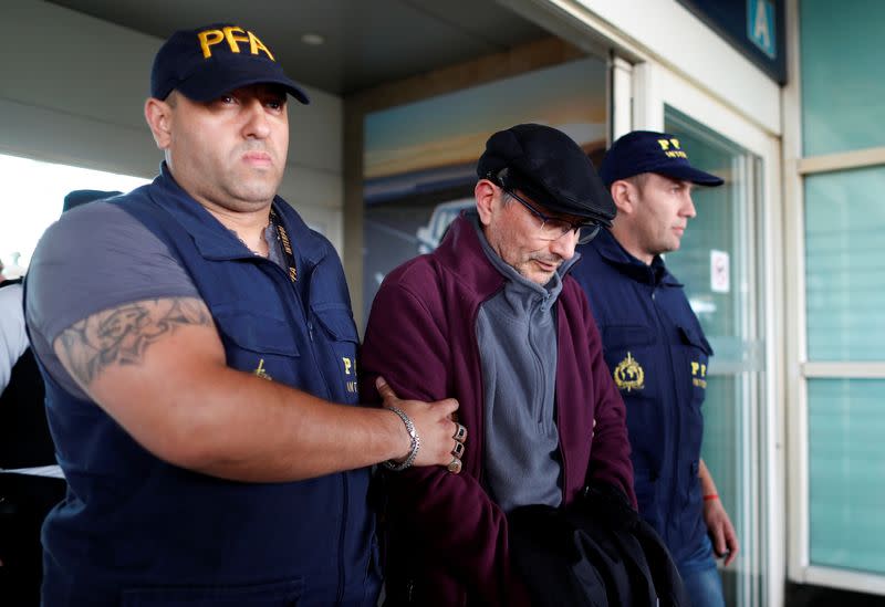 Mario Sandoval is escorted by police officers after being extradited from France, in Buenos Aires