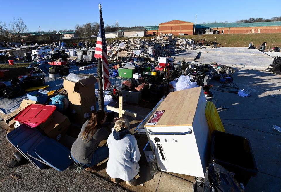 Stephanie Coble, left, and Kaylee Davis, 16, kneel by a cross in memory of 10-year-old Arlan Coty Monday, Dec. 11, 2023, in Clarksville, Tenn. Arlan died when a tornado destroyed his parents, Kyle and Katherine Burnham, home on Saturday.