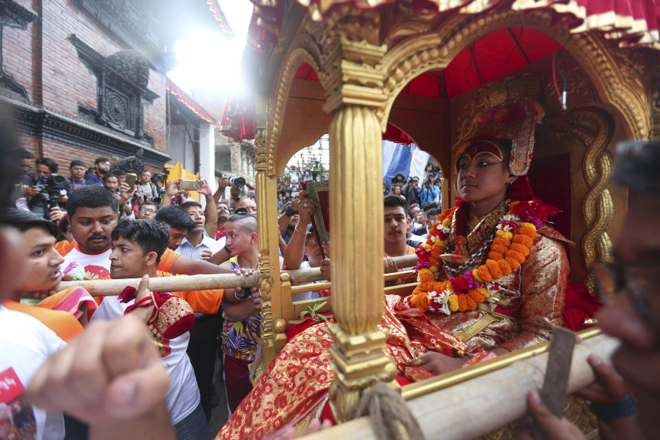 Devotees carry the chariot of living god Bhairabh during Indra Jatra festival, an eight-day festival that honors Indra, the Hindu god of rain, in Kathmandu, Nepal, Friday, Sept. 13, 2019. Families gather for feasts and at shrines to light incense for the dead, and men and boys in colorful masks and gowns representing Hindu deities dance to the beat of traditional music and devotees' drums, drawing tens of thousands of spectators to the city's old streets. (AP Photo/Niranjan Shrestha)