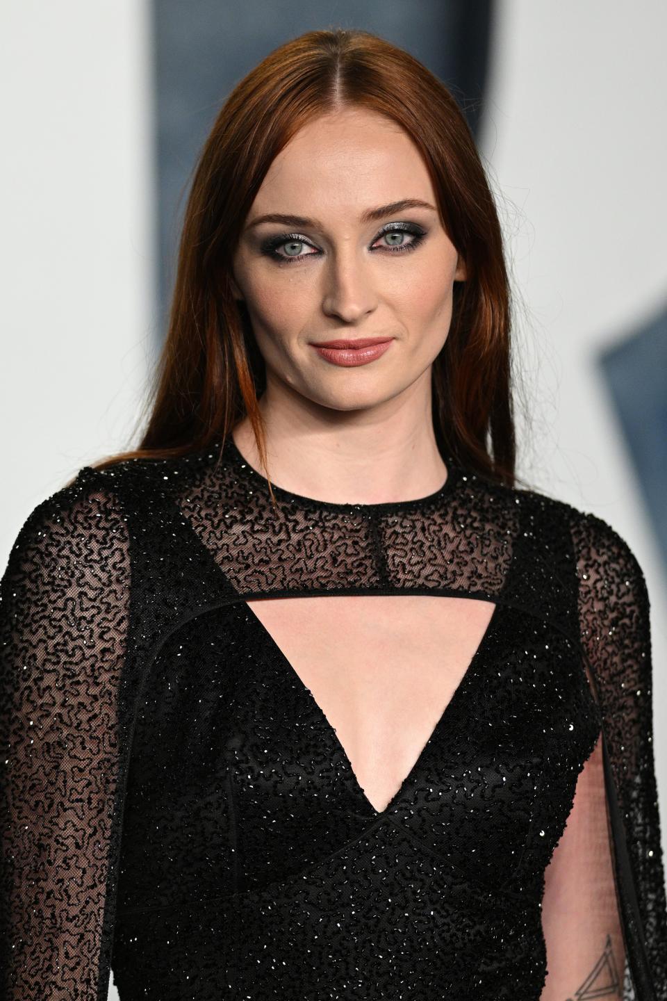 Sophie Turner in a black lace dress at an event