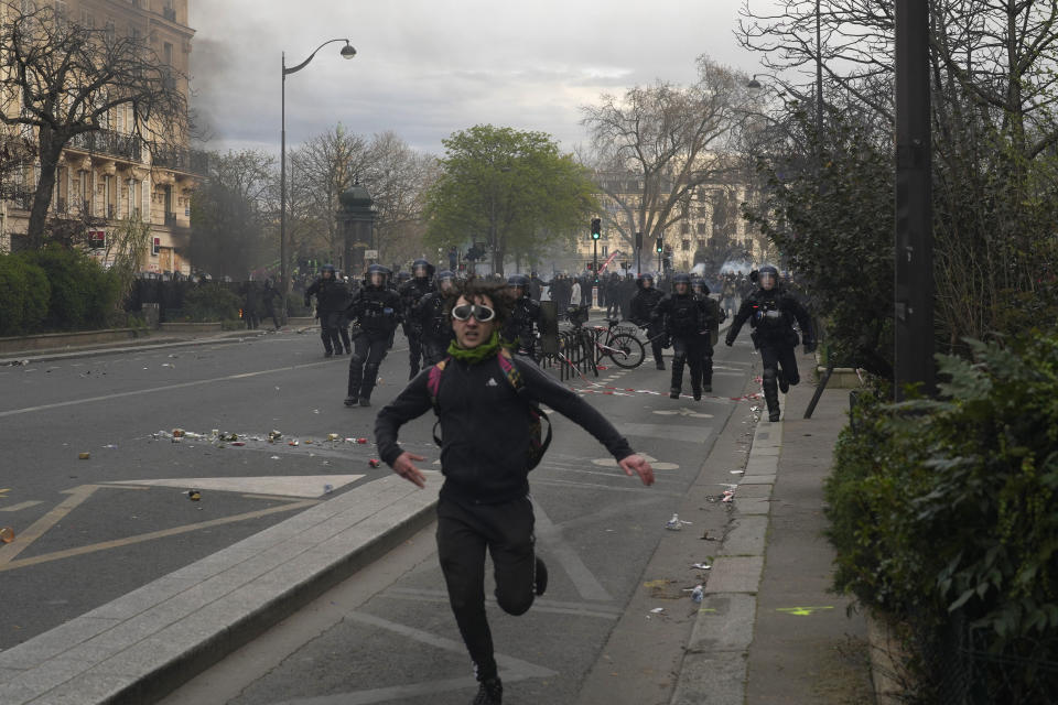 A protester is chased by riot police officers after a demonstration Tuesday, March 28, 2023 in Paris. It's the latest round of nationwide demonstrations and strikes against unpopular pension reforms and President Emmanuel Macron's push to raise France's legal retirement age from 62 to 64. (AP Photo/Thibault Camus)