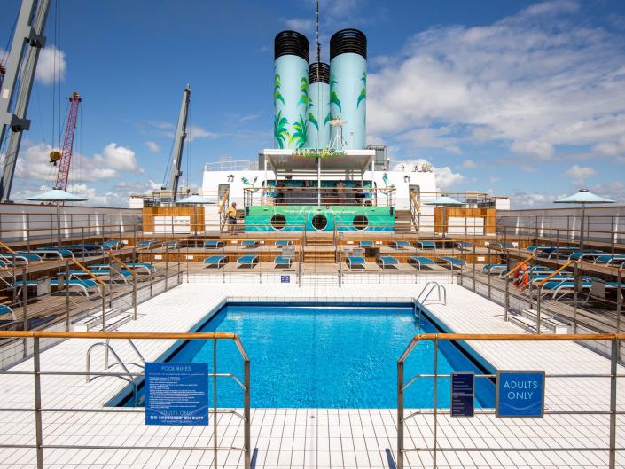 Lounge chairs surrounding a pool on a cruise ship.