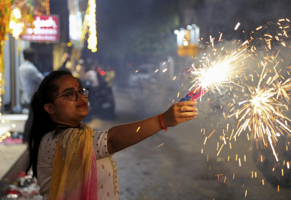 A girl lights firecrackers as she celebrates Diwali, the festival of lights, in Hyderabad, India, Thursday, Nov. 4, 2021. Hindus light lamps, wear new clothes, exchange sweets and gifts and pray to goddess Lakshmi during Diwali, the festival of lights. (AP Photo/Mahesh Kumar A.)