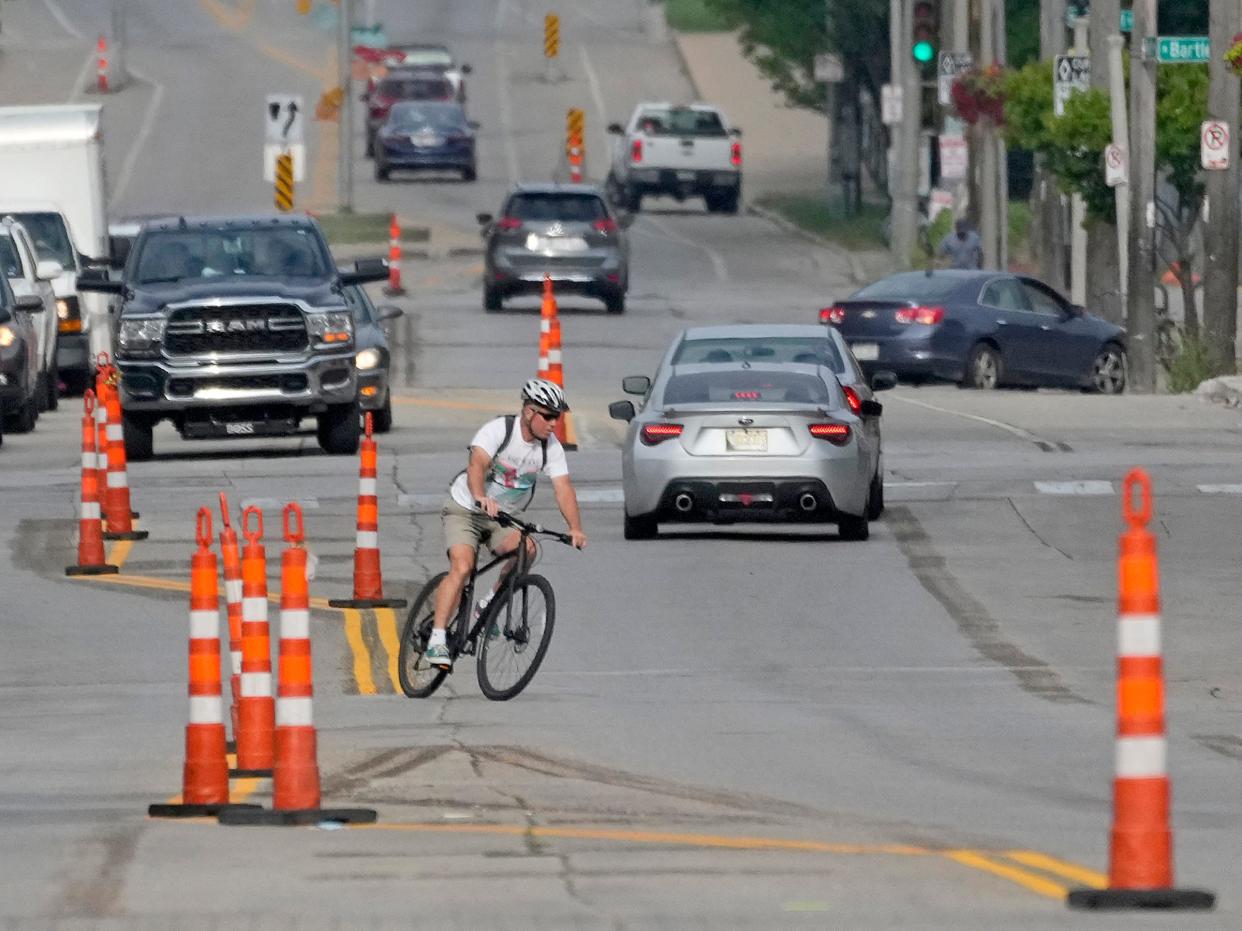 A cyclist rides their bike across East North Avenue and North Bartlett Avenue in Milwaukee on Monday, Aug. 7, 2023. Protected bike lanes are being created to help reduce the volume and severity of car crashes.
