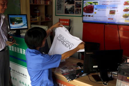 A customer looks at a T-shirt she bought at an Alibaba rural service centre in Jinjia Village, Tonglu, Zhejiang province, China, July 20, 2015. REUTERS/Aly Song