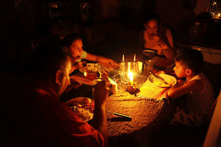 Lisney Albornoz (2nd R) and her family use a candle to illuminate the table while they dine, during a blackout in San Cristobal, Venezuela March 14, 2018. Picture taken March 14, 2018. REUTERS/Carlos Eduardo Ramirez