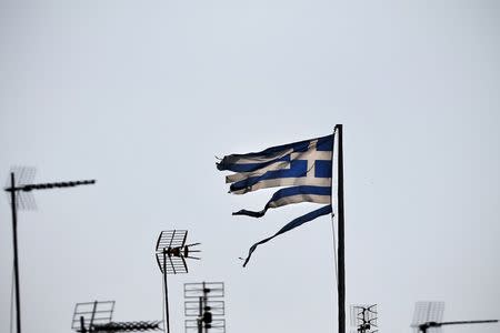 A frayed Greek national flag flutters among antennas atop a building in central Athens, Greece July 20, 2015. REUTERS/Alkis Konstantinidis