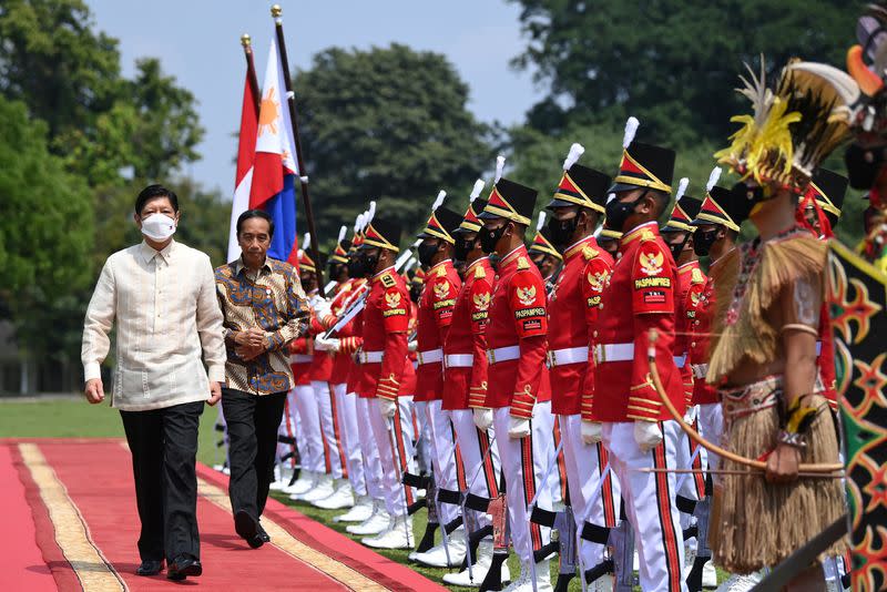 Indonesian President Joko Widodo walks with Philippine President Ferdinand "Bongbong" Marcos Jr. as they inspect the honour guards upon their arrival at the Presidential Palace in Bogor