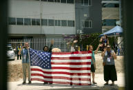 Well-wishers hold an American flag as U.S. Vice President Mike Pence's motorcade travels through Port Moresby, Papua New Guinea, Saturday, Nov. 17, 2018. (AP Photo/Mark Schiefelbein)