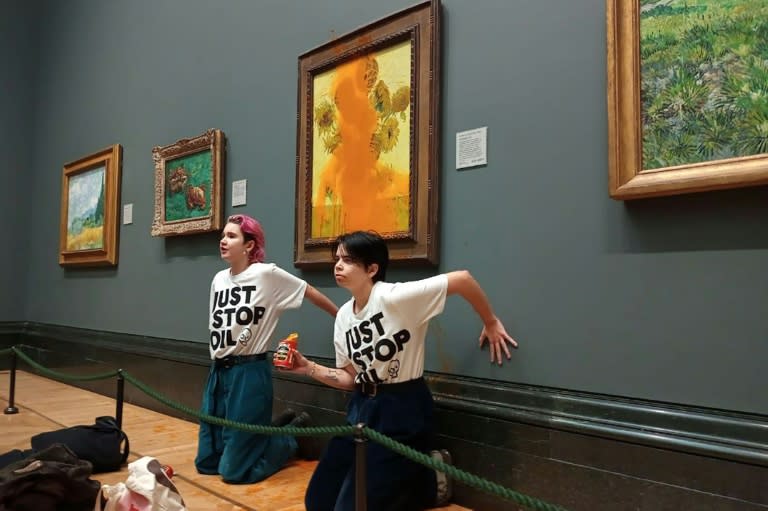 Dos activistas de la organización Just Stop Oil se pegan las manos a la pared tras rociar sopa de tomate sobre el cuadro de Vincent van Gogh "Los girasoles", en la National Gallery de Londres, el 14 de octubre de 2022 (Handout)