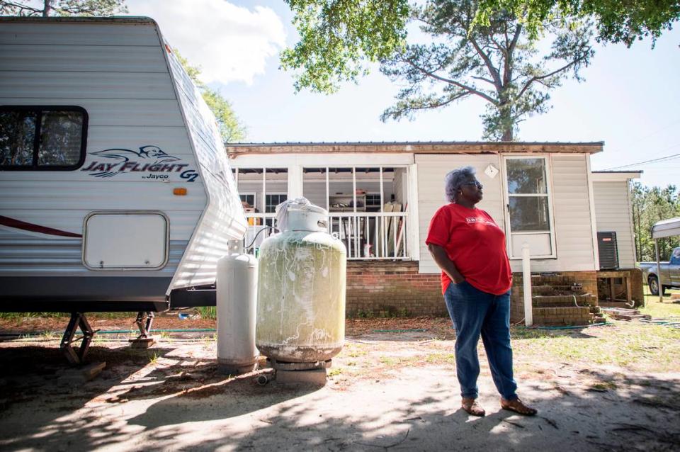 Jacqueline Hand stands outside her home next to the travel trailer she and her family are living in off Whitestocking Road near Burgaw, N.C., on Monday, April 27, 2020. Hand’s home was inundated with flood waters during Hurricane Florence and she and her family have yet to move back in almost two years later. Delays in permitting and difficulty securing contractors prevented repairs for almost a year, therefore volunteer groups were a huge help. However, now that the renovation is nearing the finish line, COVID-19 has forced volunteer organizations to pull people out of the area.