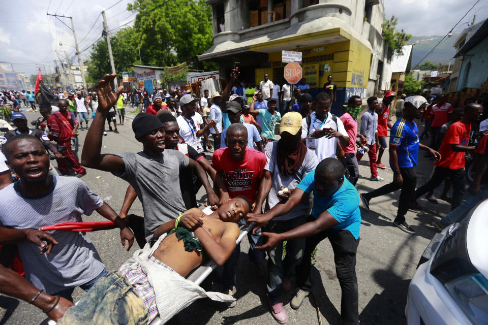 Anti-government protesters carry the body of man toward the vehicle of police, who they blame for his death, during a demonstration in Port-au-Prince, Haiti, Sunday, June 9, 2019. Protesters denouncing corruption paralyzed much of the capital as they demanded the removal of President Jovenel Moise. (AP Photo/Dieu Nalio Chery)