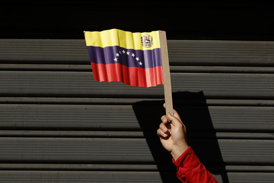 A Government supporter holds a paper Venezuelan flag during an event marking the anniversary of the 1958 coup that overthrew dictator Marcos Perez Jimenez in Caracas, Venezuela, Tuesday, Jan. 23, 2024. (AP Photo/Jesus Vargas)