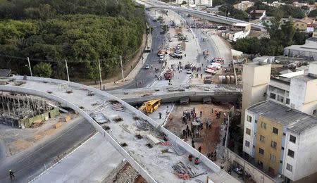 Rescue workers try to reach vehicles trapped underneath a bridge that collapsed while under construction in Belo Horizonte July 3, 2014. REUTERS/Carlos Greco-DYN