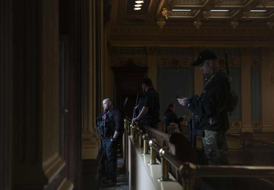 In this April 30, 2020, photo, members of a militia group watch the protest outside while waiting for the Michigan Senate to vote at the Capitol in Lansing, Mich. Gun-carrying protesters have been a common sight at some demonstrations calling for coronavirus-related restrictions to be lifted. But an armed militia’s involvement in an angry protest in the Michigan statehouse Thursday marked an escalation that drew condemnation and shone a spotlight on the practice of bringing weapons to protest. (Nicole Hester/MLive.com/Ann Arbor News via AP)