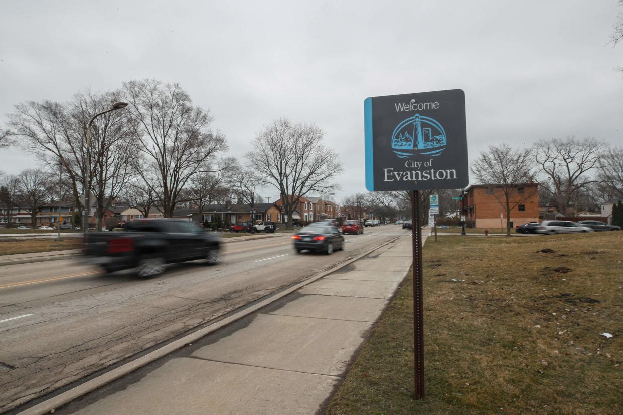 Cars drive past a sign welcoming people to the city of Evanston, Illinois.