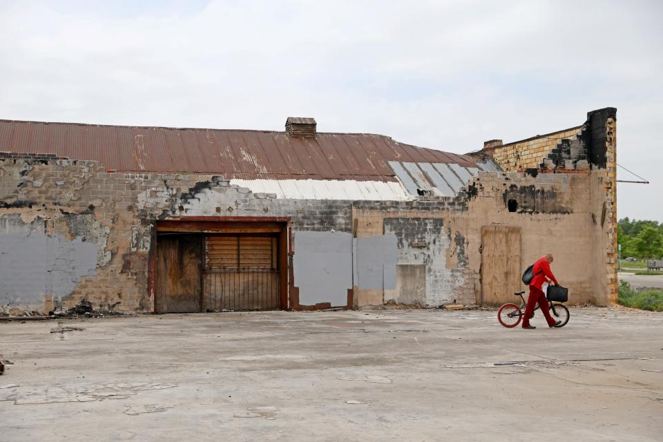 A bicyclist walks past the blighted buildings located across from Scissortail Park, which is set to host NBA playoff festivities.